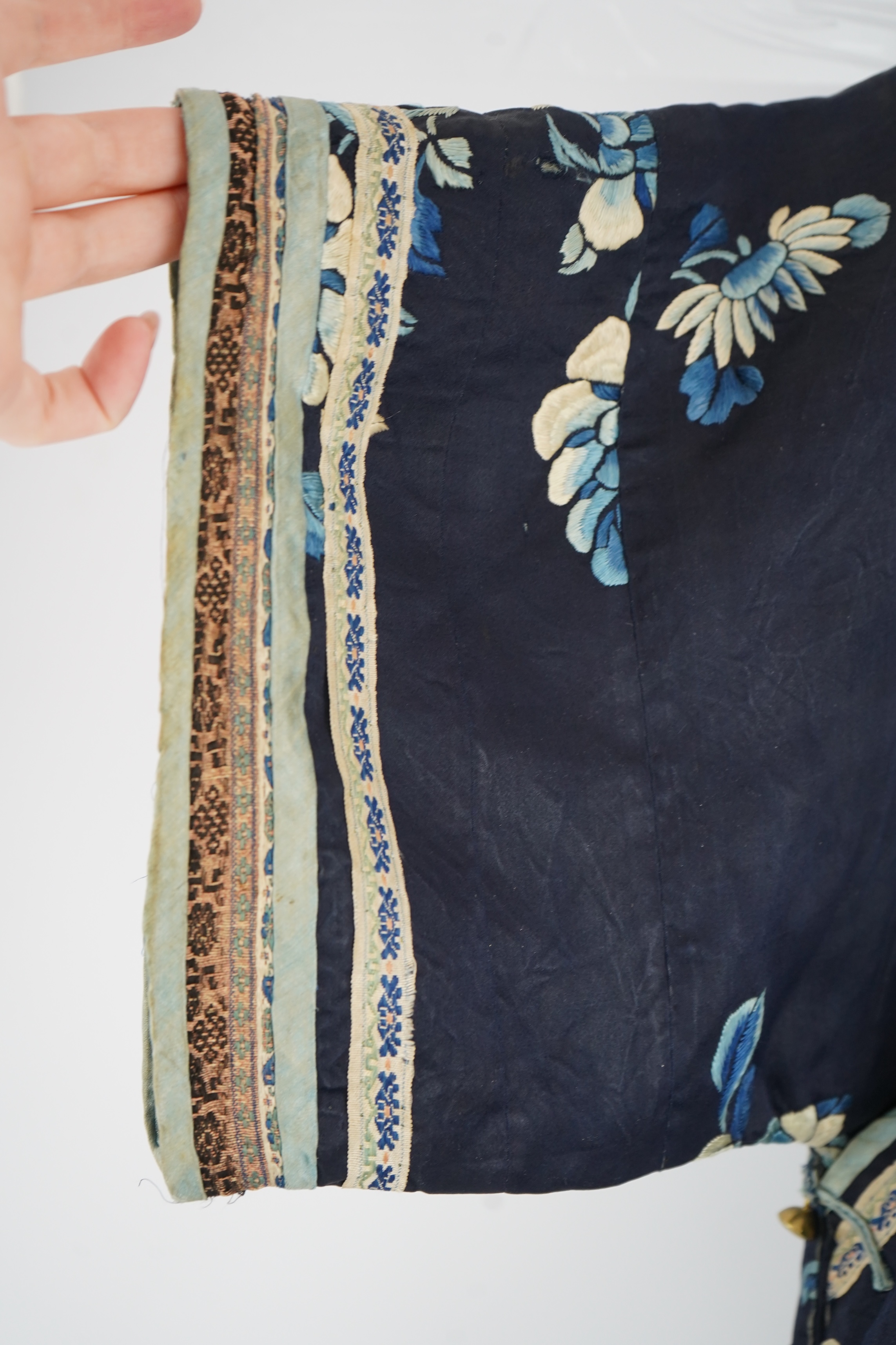 An early 20th century blue silk embroidered Chinese child’s robe, embroidered with bats and flower motifs, bordered with rows of silk braid. Condition - the original silk lining has been removed, it may benefit from bein